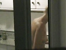 Window shot of a naked woman in the kitchen