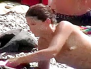 Slender and youthful black brown hair babe on the nudist beach topless