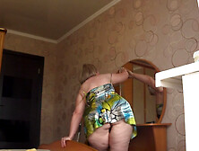 A neighbor watches a mature housewife through an open window.